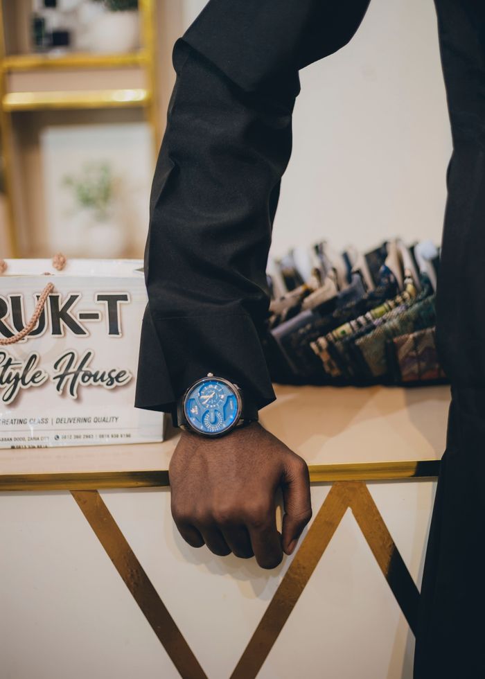 Close-up of a man's hand wearing a watch in a modern fashion boutique with fabric swatches.